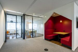 Moderne kantoorruimte aan de Johan Huizingalaan met glazen vergaderruimtes en een rood ingerichte zitnis.